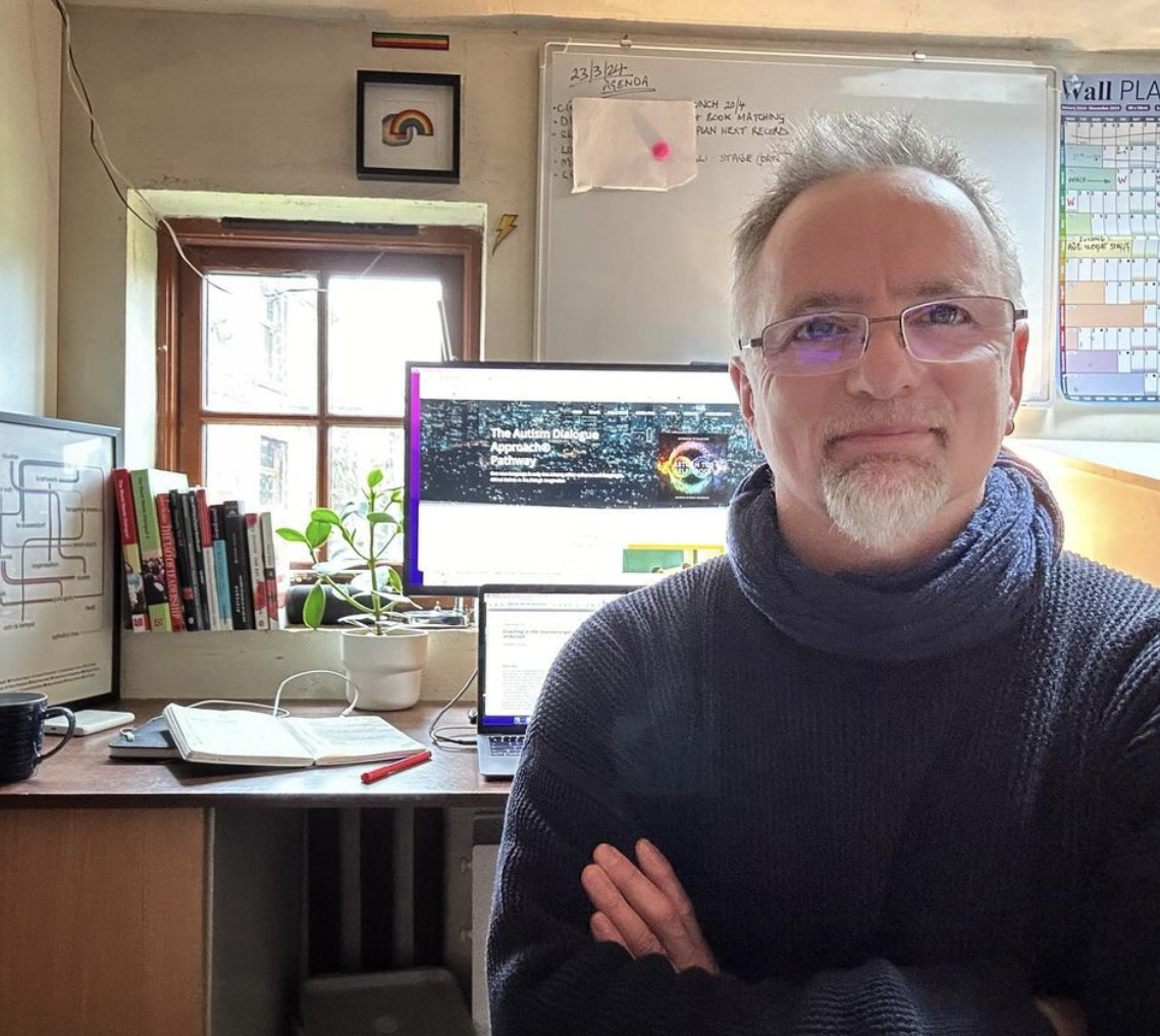 Jonny Drury white guy smiling in 40's with beard and arms folded with computer and window behind